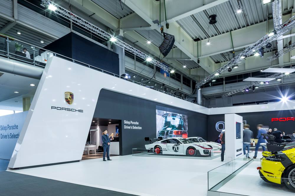 Realizacja zabudowy dla wiodących marek motoryzacyjnych podczas Poznań Motor Show to monumentalny projekt o łącznej powierzchni przekraczającej 4500 m². Jako BWS EXPO zapewniliśmy kompleksowe wsparcie techniczne i wykonawcze, tworząc spójne, a jednocześnie unikalne przestrzenie ekspozycyjne dla marek takich jak BMW, Porsche, Audi, Rolls-Royce oraz całej grupy Volkswagen (Skoda, Seat, VW). Kluczowe aspekty techniczno-wykonawcze: Skala i Logistyka: Równoczesna budowa stoisk dla wielu marek premium wymagała perfekcyjnej koordynacji prac montażowych oraz logistyki materiałowej w kilku halach targowych. Design i Materiały: Każda przestrzeń została wykończona zgodnie z rygorystycznymi standardami wizualnymi (Corporate Identity) poszczególnych brandów. Wykorzystano m.in. eleganckie okładziny drewniane dla stref luksusowych (Rolls-Royce, Porsche), nowoczesne konstrukcje loftowe oraz wysokiej jakości posadzki targowe. Systemy Podwieszeń i Multimeadia: Zastosowano zaawansowane konstrukcje kratownicowe z wielkoformatowymi ekranami LED, dynamicznym oświetleniem scenicznym oraz potężnymi elementami brandingowymi (np. charakterystyczne ringi Volkswagen Financial Services czy kubiki BMW), które zapewniały widoczność marek z dużej odległości. Strefy Specjalne: Realizacja objęła budowę dwupoziomowych stref VIP, butików Lifestyle Shop (BMW), profesjonalnych recepcji z grafikami oraz interaktywnych stoisk usług finansowych. Dzięki doświadczeniu w obsłudze największych wydarzeń motoryzacyjnych, dostarczyliśmy infrastrukturę, która połączyła technologiczną nowoczesność z prestiżem, tworząc idealne tło dla premier motoryzacyjnych najwyższej klasy.