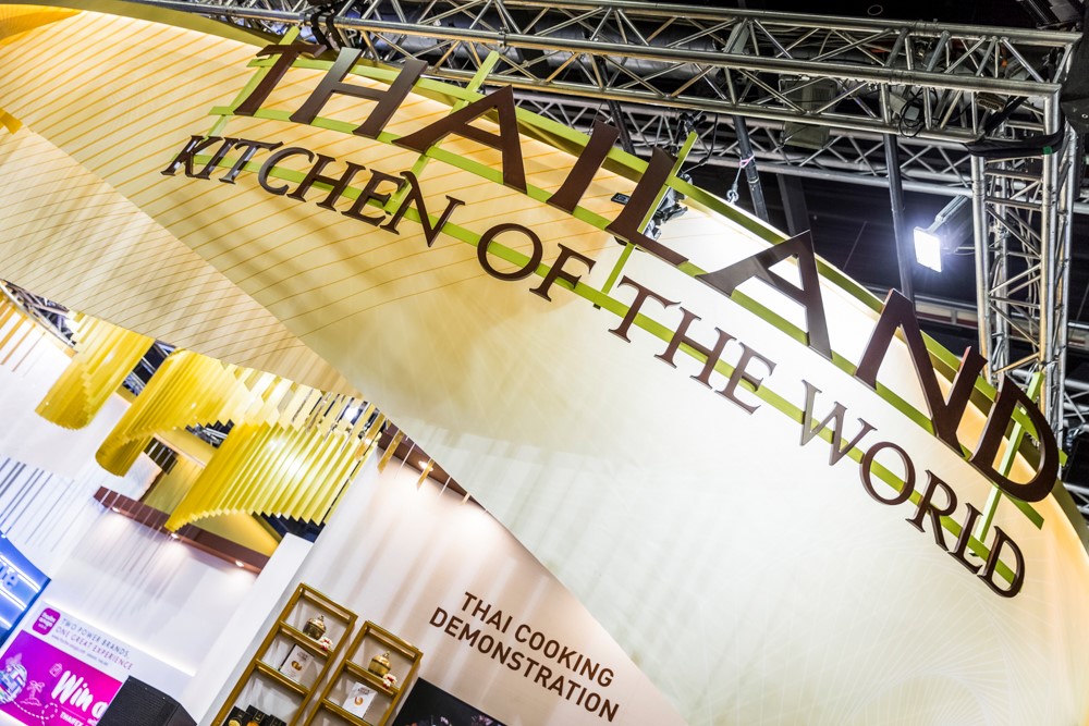 Realizacja pawilonu Tajlandii na targach Anuga 2019 objęła kompleksowe wykonanie zabudowy o powierzchni 1538 m², łączącej setki indywidualnych stanowisk w spójną architektonicznie całość. Kluczowym wyzwaniem technicznym był montaż wielkoskalowych, dynamicznych podwieszeń o złożonej geometrii, które wymagały precyzyjnej instalacji na systemach kratownicowych. Ściany wykończono wysokiej jakości laminatami i grafikami wielkoformatowymi, integrując w nich liczne wnęki ekspozycyjne z dedykowanym oświetleniem LED typu spotlight. Jako BWS EXPO wykonaliśmy pełną infrastrukturę techniczną, w tym instalacje elektryczne i wodne dla stref show cooking, zabudowę lad informacyjnych z podświetleniem ambientowym oraz montaż systemowych modułów wystawienniczych o wysokim standardzie estetycznym. Całość prac montażowych została przeprowadzona z dbałością o detale wykończeniowe i rygorystyczne normy bezpieczeństwa obowiązujące na terenie Koelnmesse.